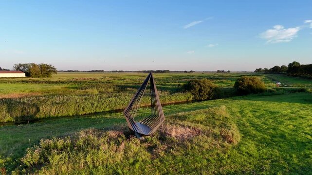 A scenic drone shot capturing the historic former island of Schokland in the Netherlands on a bright, sunny day. Schokkers monument, dedicated to the people who died on the island. Rotating shot