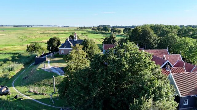 A scenic drone shot capturing the historic former island of Schokland in the Netherlands on a bright, sunny day.Rotating shot of church revealing the tiny village and a boat.