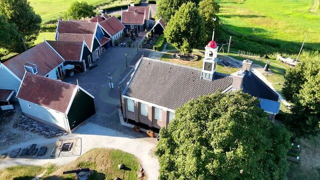 A scenic drone shot capturing the historic former island of Schokland in the Netherlands on a bright, sunny day. Slow pull back of church and other buildings.