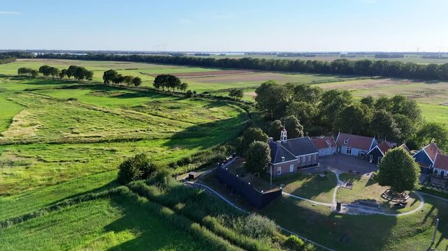 A scenic drone shot capturing the historic former island of Schokland in the Netherlands on a bright, sunny day. Flying over the church, tilting to the bell tower.
