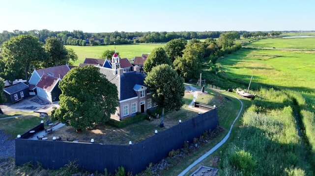 A scenic drone shot capturing the historic former island of Schokland in the Netherlands on a bright, sunny day. Dolly shot of the church, revealing the wall.