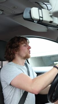 Vertical screen inexperienced driver anxiously checks nearby traffic while driving through the city showing worry uncertainty and low confidence behind the steering wheel
