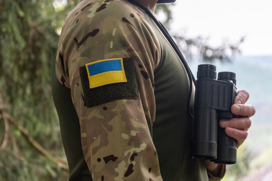 Ukrainian soldier holding binoculars during outdoor observation mission