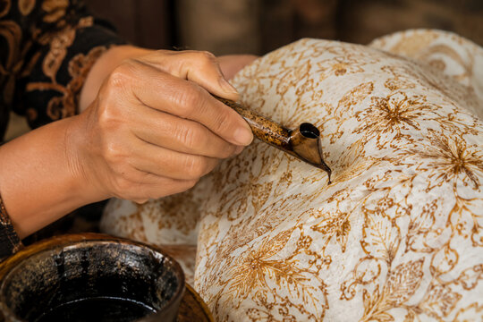 artisan painting traditional Indonesian batik tulis fabric using a canting tool