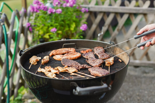 Man hands grilling diverse meat on barbecue outdoor during summer weekend day - Food, vacation and family party concept