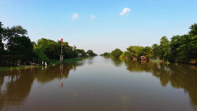 Peaceful aerial sweep over still river surface reflecting clear blue sky