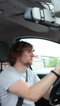 Vertical screen sleepy driver travels through the city with heavy eyelids and a tired expression while struggling to remain attentive during a routine journey on the road