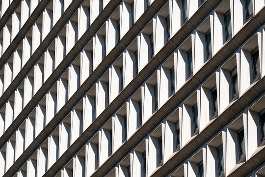 Facade detail of modern architecture where diagonal geometry frames windows across an exterior pattern with shadows and strong visual repetition
