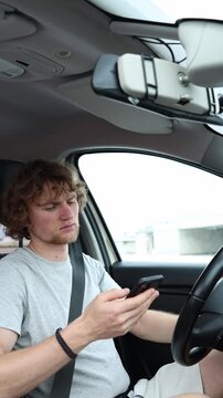 Vertical screen driver frequently checks his smartphone while traveling through the city showing a dangerous habit of losing focus on traffic during everyday car journeys