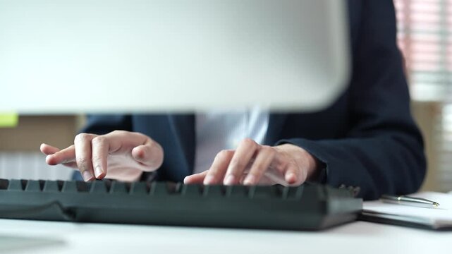 Close-up of businessman hands typing on a desktop computer keyboard while sitting at an office desk, illustrating corporate work, data entry, and business communication