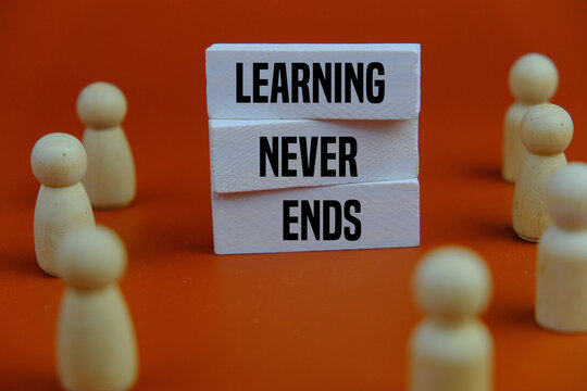 Concept words Learning never ends on white wooden blocks. Orange background. Business support motivational and learning never ends concept. Copy space.