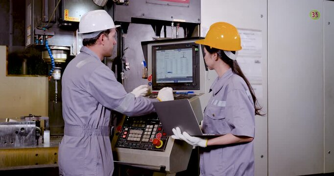 Asian engineer pair studies CNC control panel and laptop, checking program data, machine status, safety requirement, production tracking, digital workflow coordination in smart manufacturing plant.