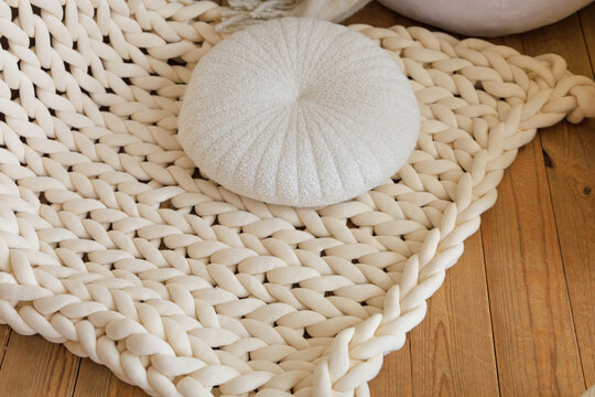 Cozy setting with a knitted rug and a round pillow on wooden floor