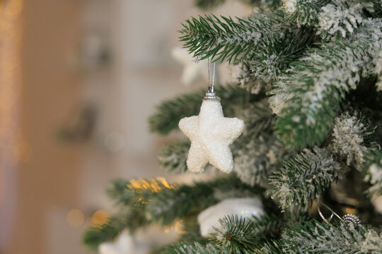 Holiday decoration with a white star ornament hanging from a green Christmas tree in a cozy setting