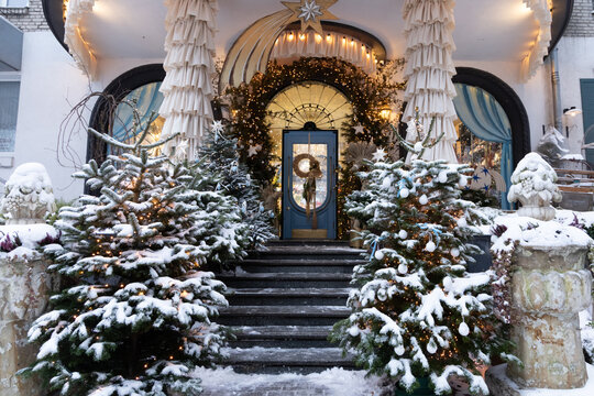 Snowy Christmas entrance decorated for winter holidays with wreath and trees outside a building