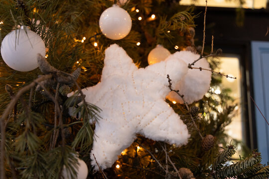 Decorative star ornament hangs on a Christmas tree during a holiday celebration in a cozy indoor space
