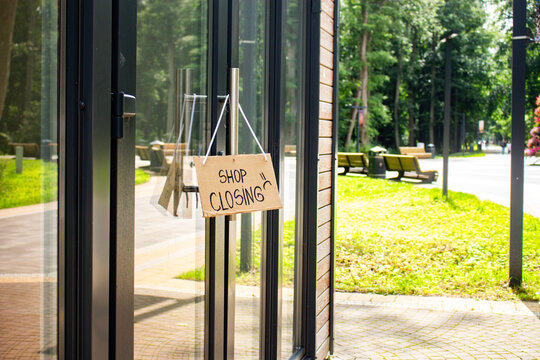SHOP CLOSING sign hanging on small shop door. Small business shutting down due to financial crisis. Local business unable to survive economic pressure