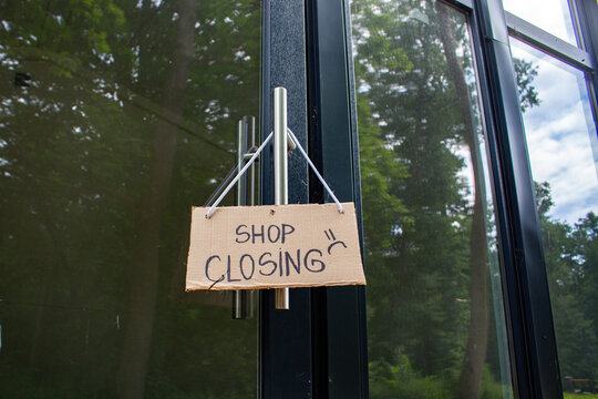 Sign SHOP CLOSING on welcome door of small shop. Local business closure. Owners facing economic struggles and client loss