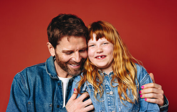 Smiling father and daughter in a warm studio portrait together