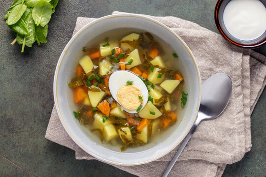 Delicious sorrel soup with leaves and egg in ceramic bowl. Spring soup with wild herbs