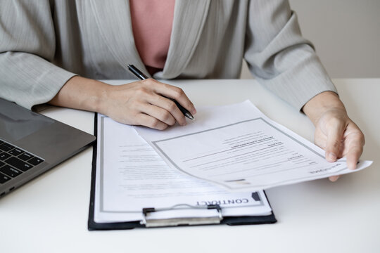 Businesswoman Reviewing Resume Documents at Office Desk with Laptop, Analyzing Candidate Information for Recruitment, Hiring and Job Interview Preparation