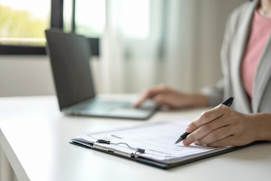 Businesswoman Reviewing Resume Documents at Office Desk with Laptop, Analyzing Candidate Information for Recruitment, Hiring and Job Interview Preparation