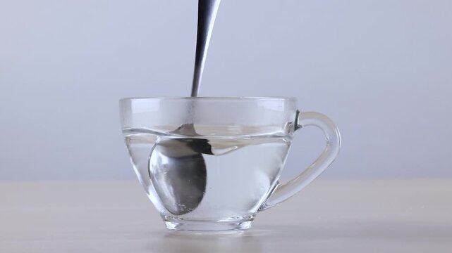 Metal Spoon Stirring Sugar into Hot Water in Glass Cup