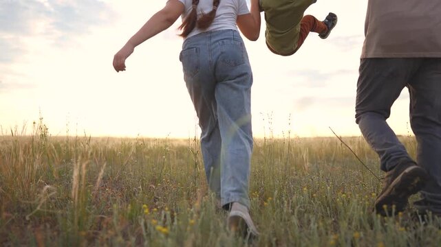 A woman, a man, and a boy walk together through tall grass. The woman holds the boy's hand while the man guides them, enjoying the scenery.
