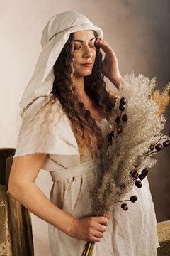 Artistic Maternity Portrait of Pregnant Woman in Medieval Gown with Dried Flowers