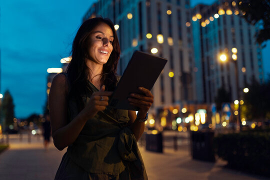 Woman using tablet connecting with urban lifestyle at night