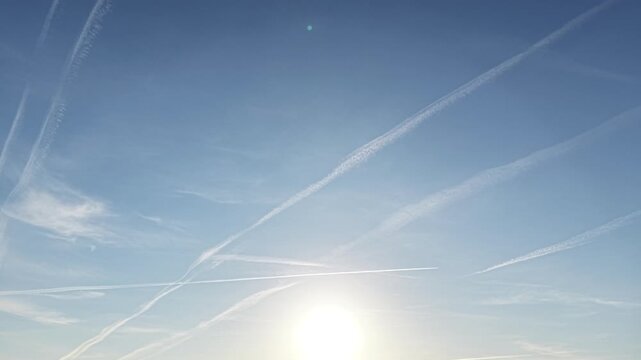 Jet trail patterns stretching through calm morning sky