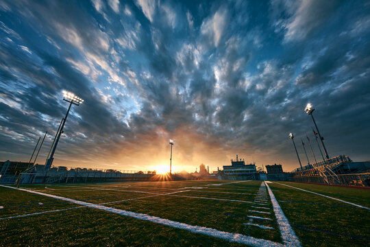 Football Field Stadium Under Dramatic Sunset Sky with Floodlights