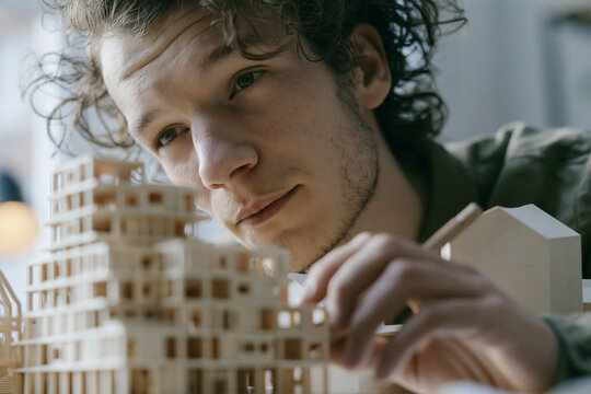 Young Male Architect Inspecting Wooden Scale Model