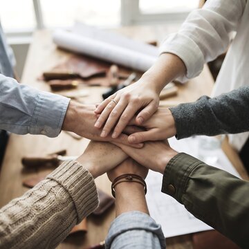 Creative Team Stacking Hands Over Workbench and Blueprints