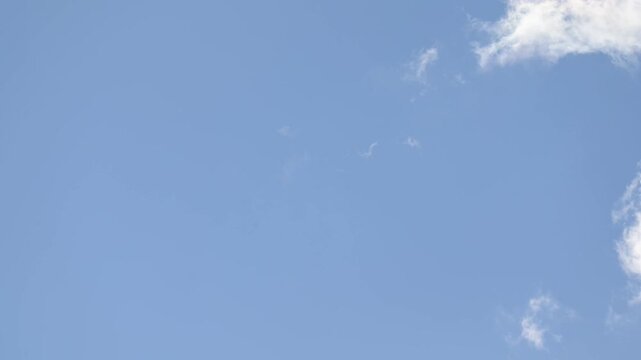 Bands of white clouds flow continuously across an open blue sky in timelapse. Smooth accelerated movement creates a versatile atmospheric background for weather and nature projects.