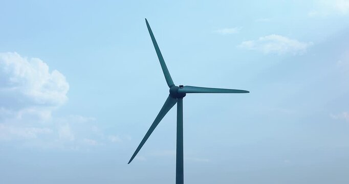 Wind turbine blades rotating against a blue sky. Renewable energy infrastructure generating clean electricity from wind power, sustainable technology and green energy concept.