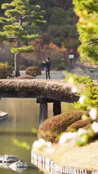 Man Taking Photos on Wooden Bridge in Japanese Garden