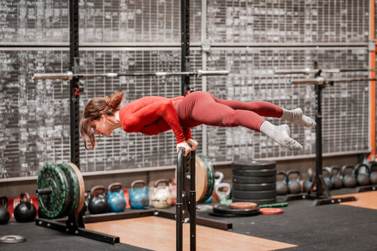 Woman performing planche exercise on parallettes in gym