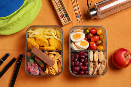 Two school lunchboxes side by side: unhealthy with nuggets, fries, chips and candy vs healthy with boiled eggs, tomatoes, grapes and crackers. Kids nutrition comparison concept