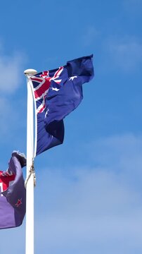 Australian and New Zealand Flags Waving Against Blue Sky