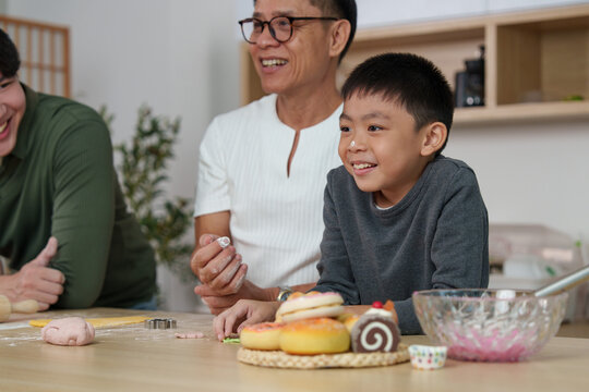 Happy Asian boy with flour on nose smiling while baking with family