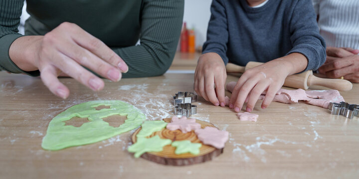 Cropped hands of family making cookies together on wooden kitchen table