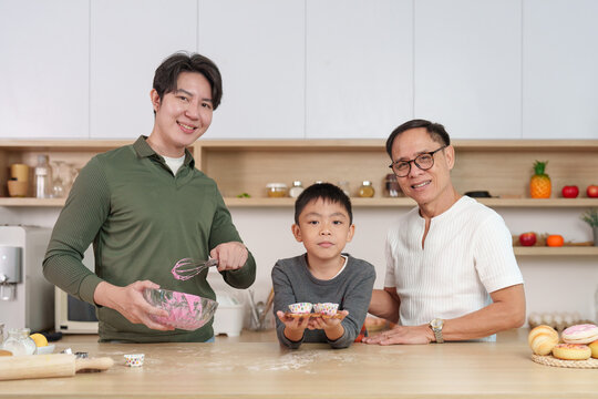 Multigenerational Asian family baking cupcakes together in home kitchen