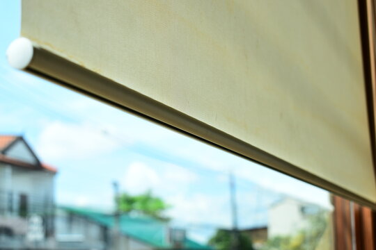 beige window roller shade bar with blurred outdoor city view