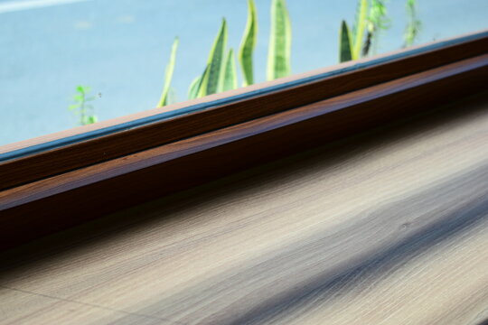 modern wooden window frame sill with green plant outside