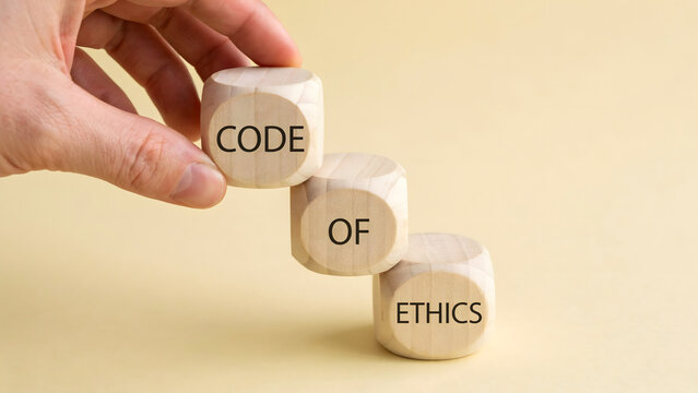 A hand placing wooden blocks to spell out the phrase code of ethics
