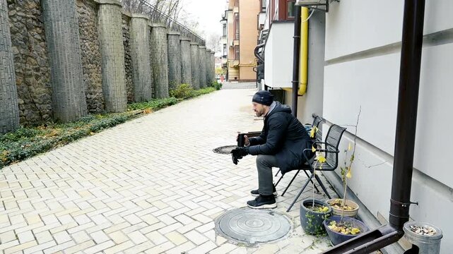 Man sitting on a folding chair in a quiet urban alleyway, relaxing or waiting