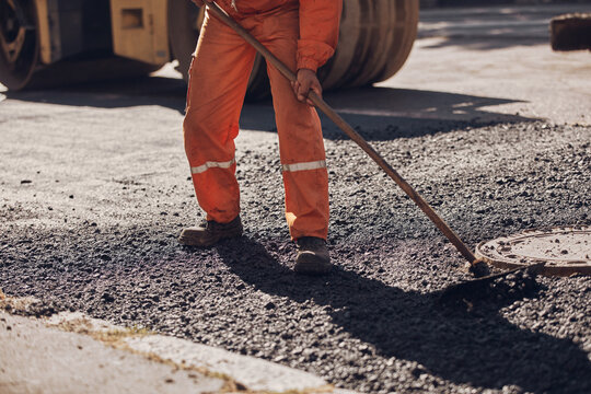 Construction workers working on a new asphalt layer on a public street.