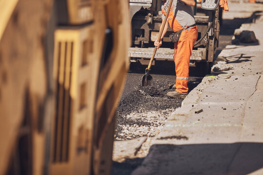 Construction workers working on a new asphalt layer on a public street.