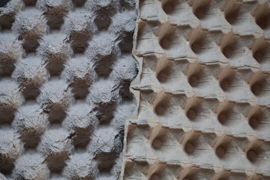 Closeup of pressed recycled cardboard egg tray texture, highlighting rough fibers, natural paper pulp, sustainable packaging, and earthy material details.